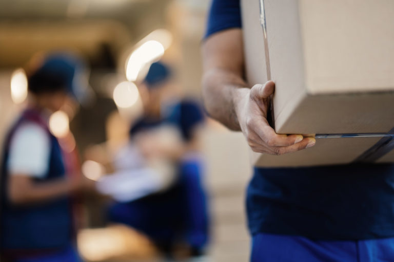 Close up of unrecognizable delivery man with cardboard box.