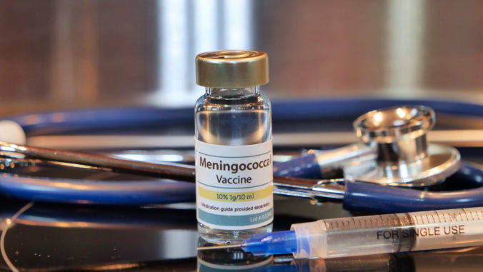Vial of Meningococcal whit syring and stethoscope stainless steel background