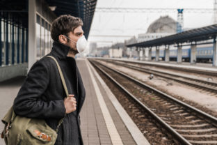 Adult caucasian male waiting in protective mask for the train arrival on station