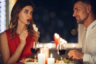 Young woman eating and flirting with her man while have romantic dinner
