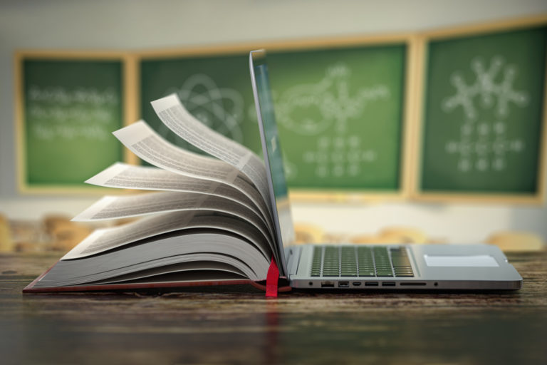 E learning online education or internet  encyclopedia concept. Open laptop and book compilation in a classroom.