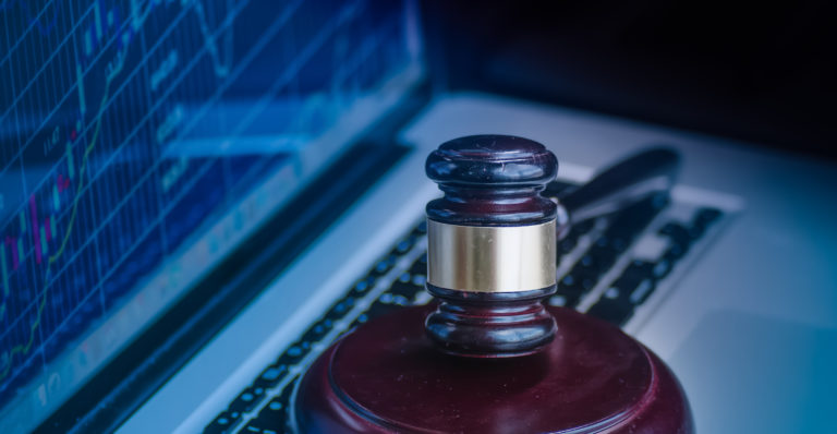 Judges gavel on keyboard with glowing computer screen monitor background.