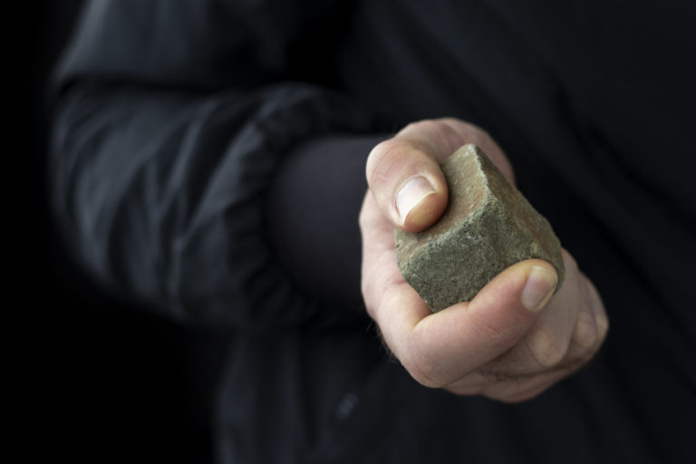 Cobblestone in male hand. Riot concept.