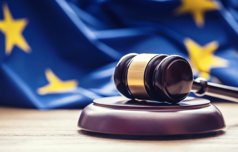 Judges wooden gavel with EU flag in the background.