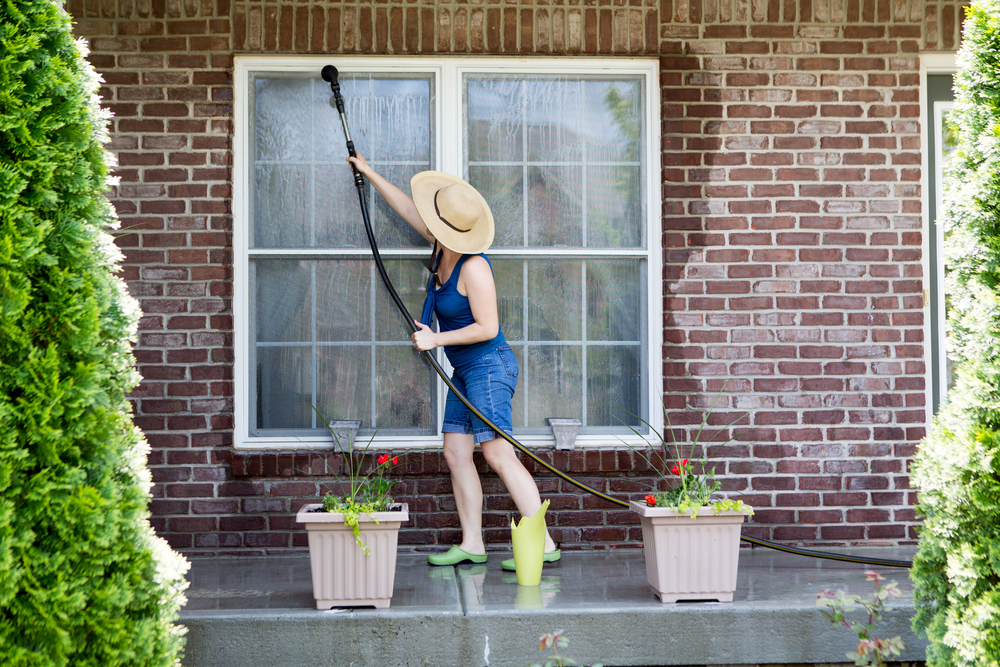 Housewife,Standing,On,A,Patio,Washing,The,Windows,Of,Her