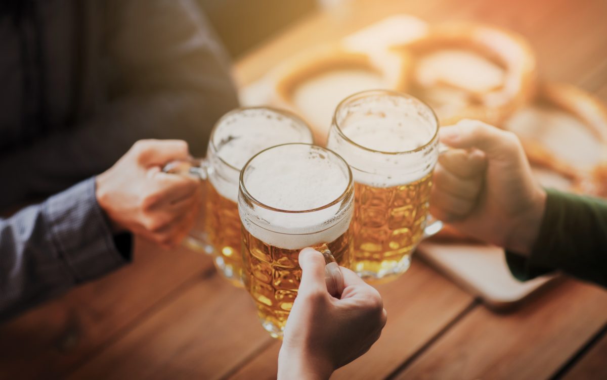 Close up of hands with beer mugs at bar or pub