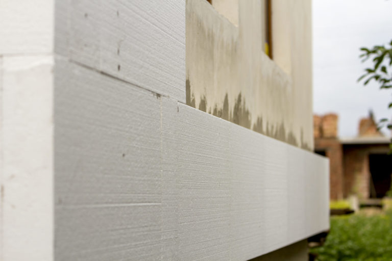 Close up detail of plastered house wall with rigid styrofoam insulation. Modern technology, construction, renovation, energy saving, alternative for mineral wool, warm comfortable house concept.