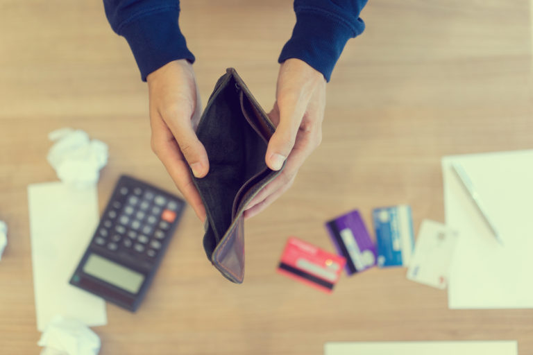 Close up man hand opening empty wallet over calculator , debt expense bills monthly and credit card at the table in home office ,  managing payroll,money risk financial concept