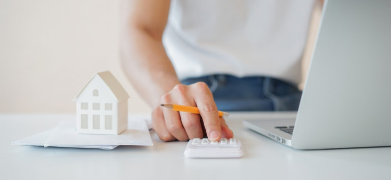 Close up man hand counting on calculator with house's model on invoice letter to summary of refinance expense for planning and manage money about home loan mortgage and interest rates for people lifestyle concept