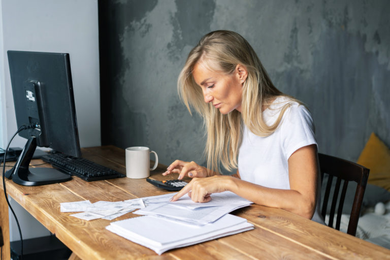 Young business woman counts on a calculator bills and amounts.