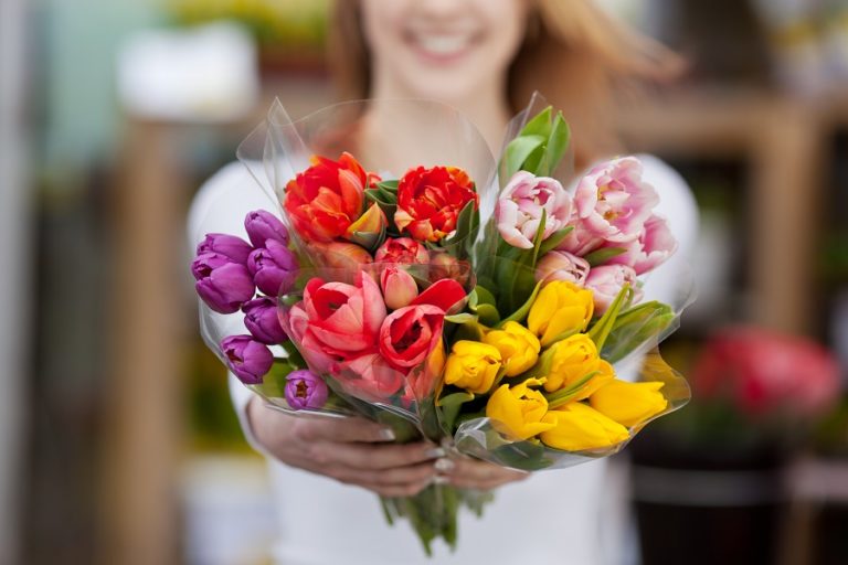 Frau zeigt blumen vom markt