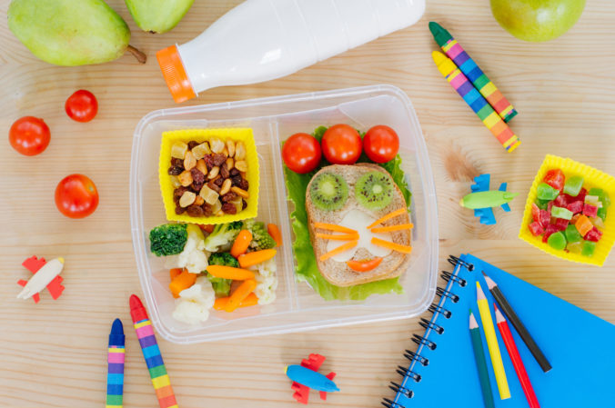 Plastic lunch box on a wooden table with school accessories