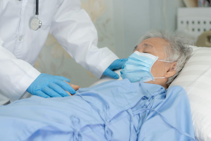 Doctor help Asian senior or elderly old lady woman patient wearing a face mask in hospital for protect safety infection and kill Novel Coronavirus (2019 nCoV) Covid 19 virus.