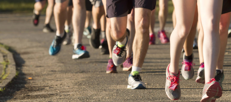 Legs of runners on a dirt path next to a lake