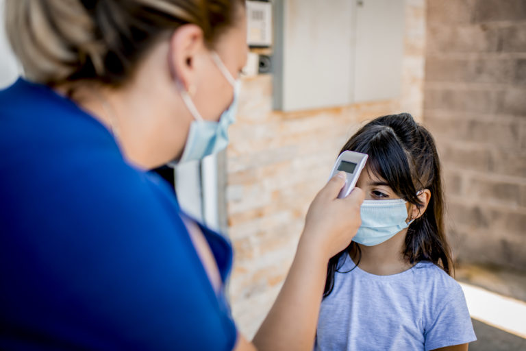 Mother measuring her daughters temperature before going to school. New normal concept