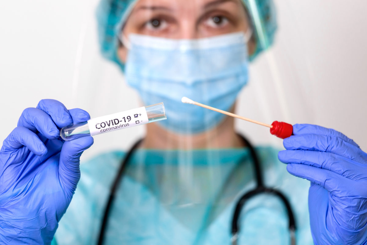 Medical healthcare holding COVID 19 , Coronavirus swab collection kit, wearing PPE protective suit mask gloves, test tube for taking OP NP patient specimen sample,PCR DNA testing protocol process