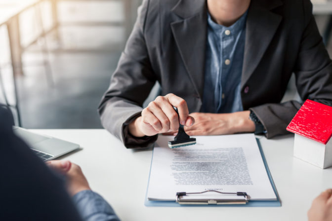 Business people approval stamp on business contract. Approval of a contract to buy or sell a home. Offers mortgage loans and home insurance concept.