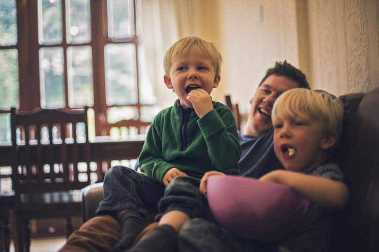 Father and sons watching television together