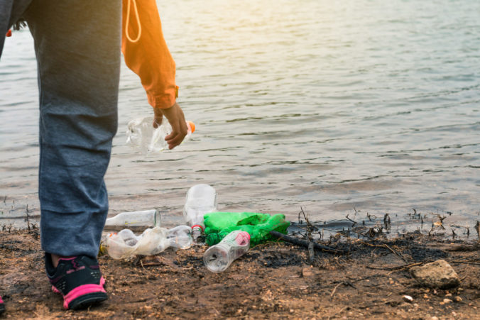 Low Section Of Volunteer Holding Plastic Bottle By Lake