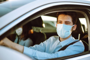 Man driving a car puts on a medical mask during an epidemic in quarantine city.