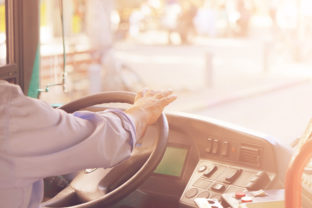 Cropped shot of bus driver holding steering whee