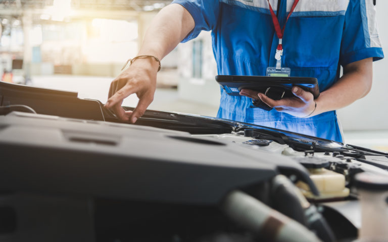 Auto mechanic uses the tablet to check.