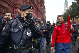 Russia Election Protest Police escort a demonstrator with a red flag during a protest against the results of the Parliamentary election near Red Square in Moscow, Russia, Saturday, Sept. 25, 2021. The Communist Party has called for a rally in Moscow on Saturday and was urged by the authorities Friday to remove the announcements from its website, otherwise it would be blocked — pressure that a party with seats in the parliament and which backs many of the Kremlin's policies has rarely faced before.