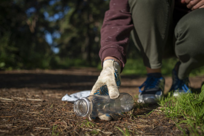 Woman collecting plastic garbage in forest