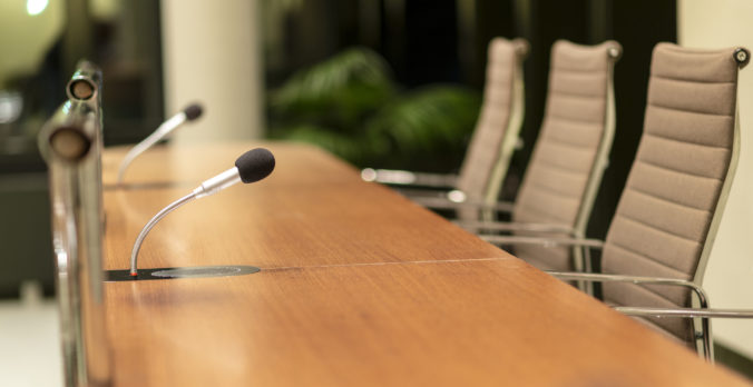 Isolated view of a microphone in the front of a conference room among blurred other mikes in the background