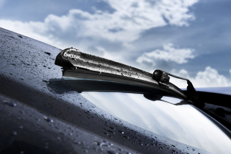 Closeup of wet windshield wiper, wipping windscreen outside
