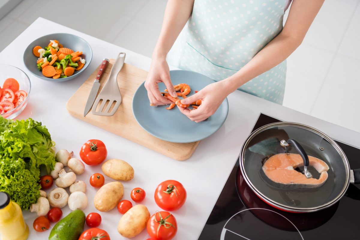 High angle view cropped photo of housewife lady desktop peeling boiled shrimps cooking family dinner prepared ingredients wear apron t shirt stand modern kitchen indoors