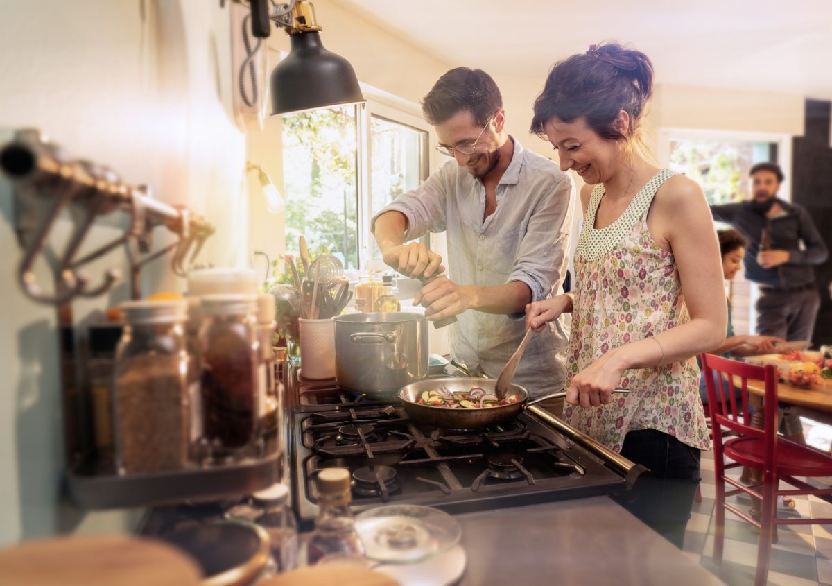 Mixed group of friends have fun while cooking a meal in kitchen