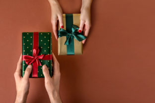 Woman giving her boyfriend a wrapped Christmas gift.Christmas giftboxes with tidewater green ribbon. Hands Giving Gifts Close up.