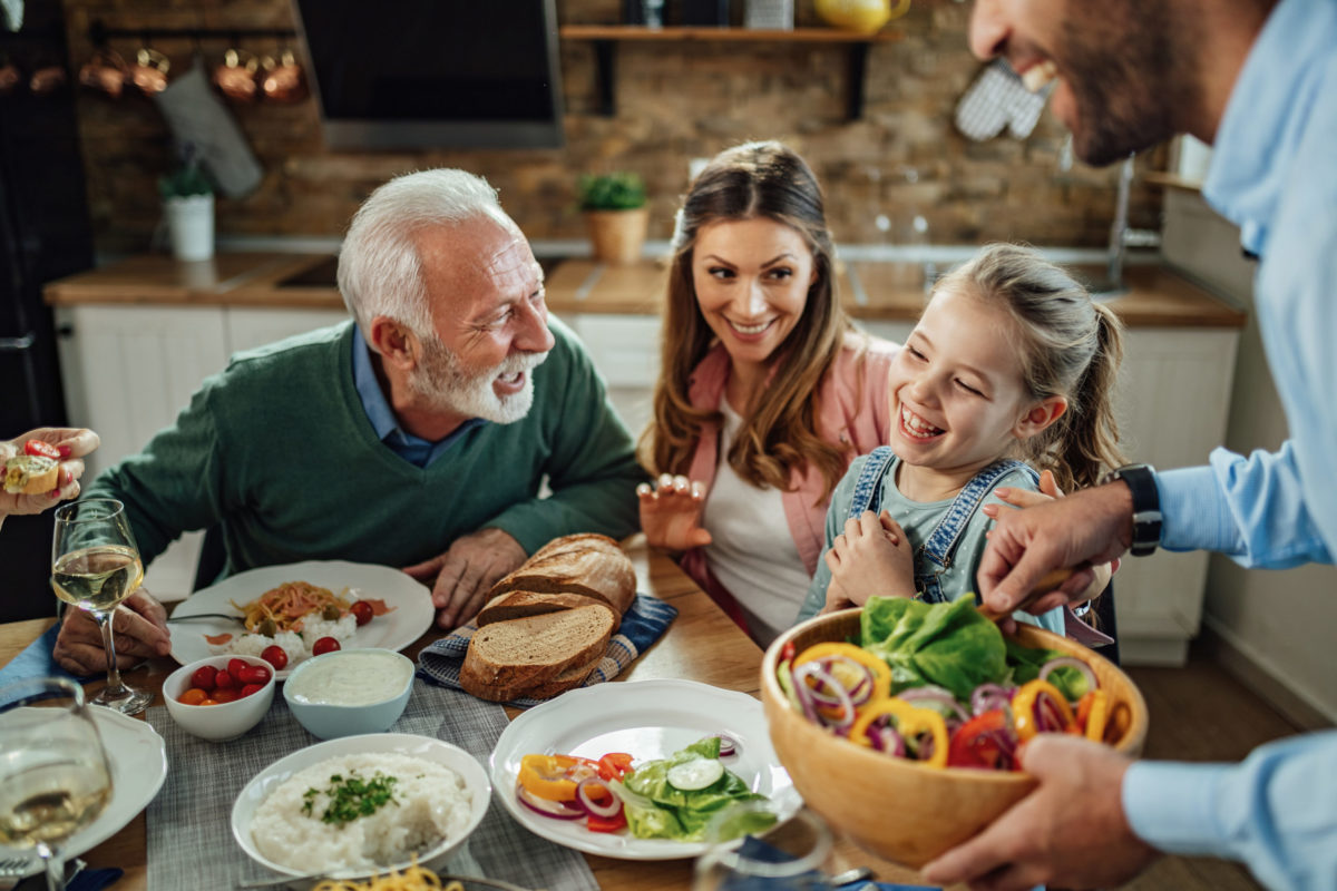 Cheerful little girl having with with her family at dining table.