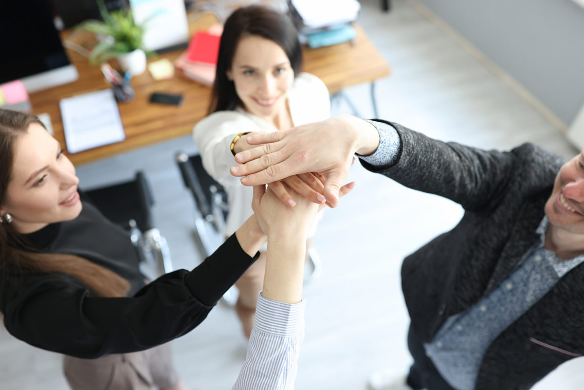 Young business people holding hands together demonstrating support and unity closeup