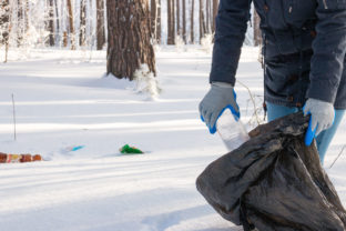 Girl collects garbage in the winter forest