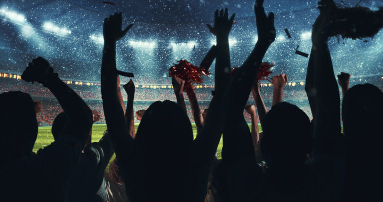 Fans celebrating the success of their favorite sports team on the stands of the professional stadium while it's snowing