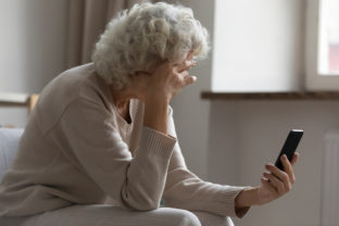 Elderly woman hold smartphone feels disappointed by received bad news