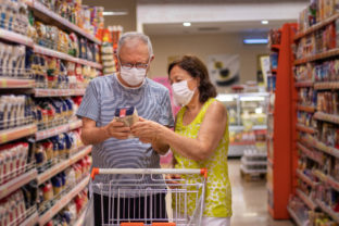 A senior couple shopping at the market with protective masks.