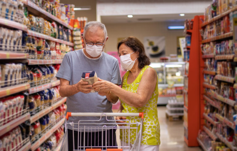A senior couple shopping at the market with protective masks.