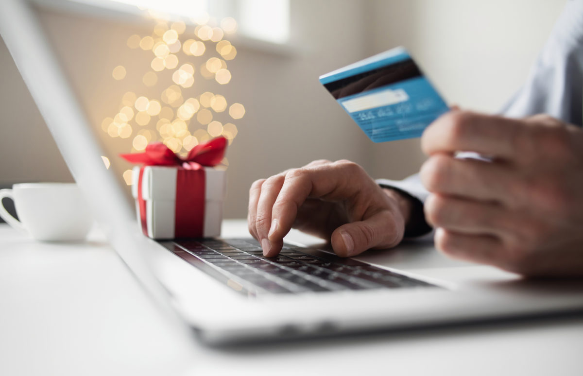 Online shopping during holidays. Man ordering Christmas gift using laptop and credit card