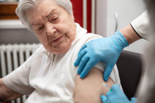 Senior adult elderly woman with grey hair is receiving a vaccination against covid, concept pandemic coronavirus protection or flu