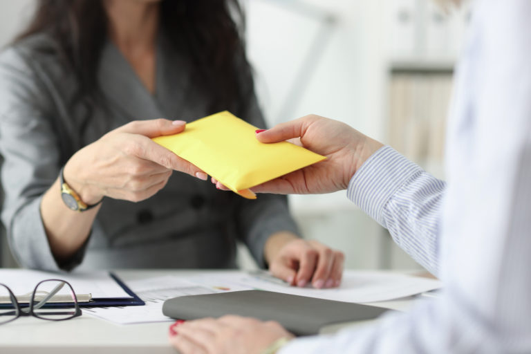 Woman hands over full envelope to her interlocutor