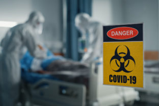 Hospital Coronavirus Emergency Department Ward: Doctors wearing Coveralls, Face Masks Treat, Cure and Save Lives of Patients. Focus on Biohazard Sign on Door, Background Blurred Out of Focus