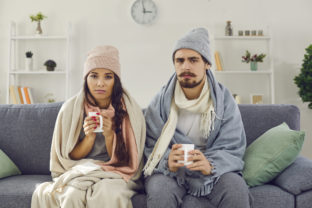 Upset young couple having problem with central heating or suffering from cold or flu