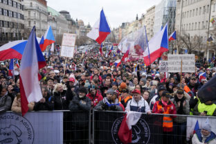 People wave flags and banners as they gather to protest against the governments restrictions to curb the spread of COVID-19 in Prague,