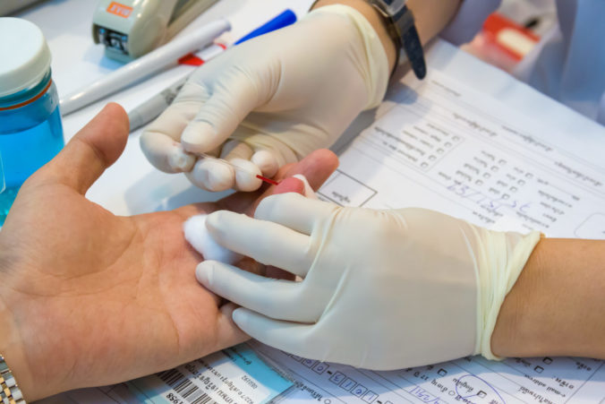 A nurse takes blood from a finger on the analysis