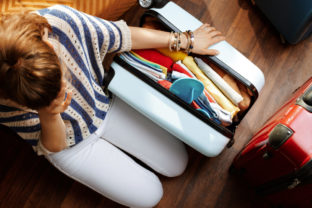 Stressed elegant woman near over packed suitcase