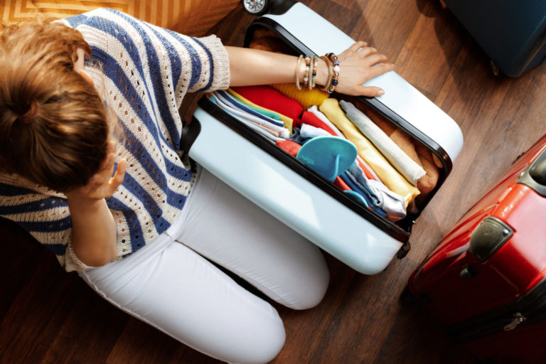 Stressed elegant woman near over packed suitcase