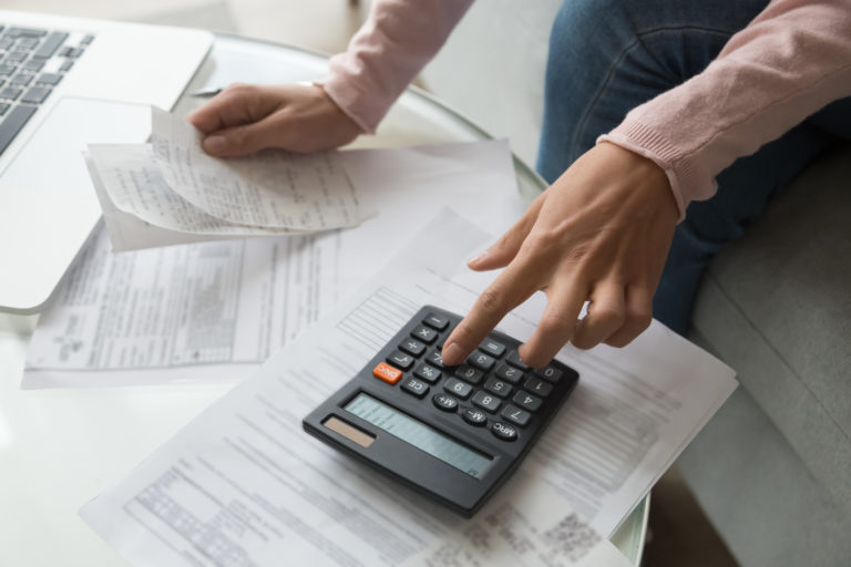 Close up woman hands holding receipt calculating company expenses